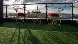 Two ornate metal chairs with red cushions on a balcony with a city view. - Smart Apartments - The Queens (Southampton)