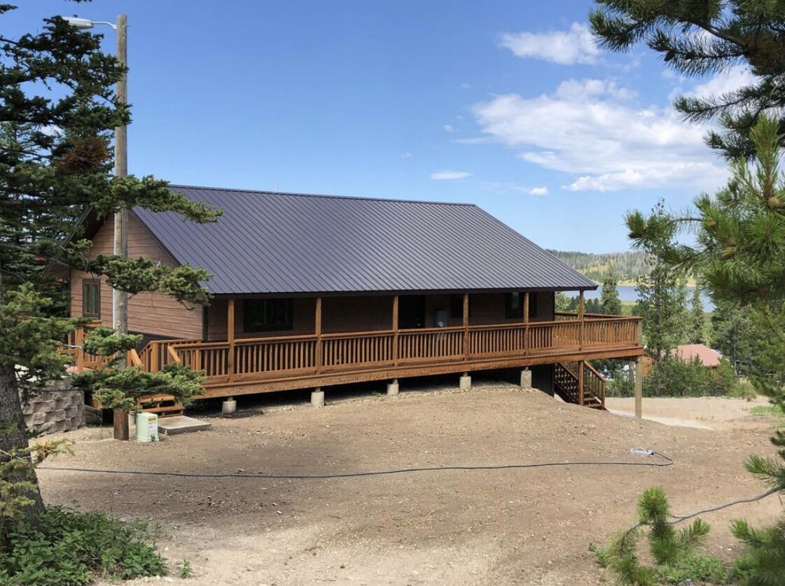 Un bâtiment à deux étages, doté d’un toit en métal et d’une terrasse en bois.