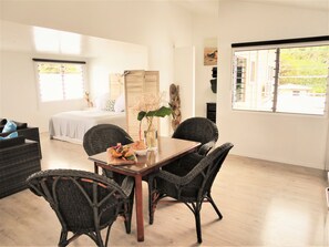 Ein Zimmer mit einem Bett, einem Esstisch mit Stühlen und einem großen Fenster.