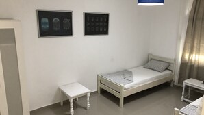 A small, clean room with a single bed, a bedside table, a wardrobe, and two framed pictures on the wall. - Mia Patria apartment (Doni Štoj)