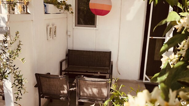 A patio area with a sofa and chairs, a window with a paper ball decoration, and potted plants. - Mia Patria apartment (Doni Štoj)