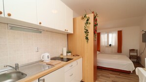 Ein kleines Hotelzimmer mit Küchenzeile, einem Bett und einer kleinen Sitzecke.