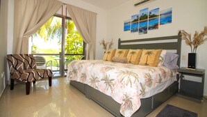 A bedroom with a bed, a chair, a nightstand, and a window with curtains. - Les Alizes near Beach (Playa del Carmen)
