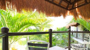 A balcony with a thatched roof, surrounded by lush green foliage. - Les Alizes near Beach (Playa del Carmen)