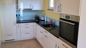 Una cocina moderna con armarios blancos, encimera negra y horno empotrado.
