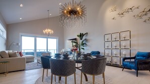A modern dining area with a round table, chairs, and a chandelier.