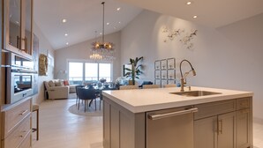 A spacious kitchen with a large island, modern appliances, and a chandelier.
