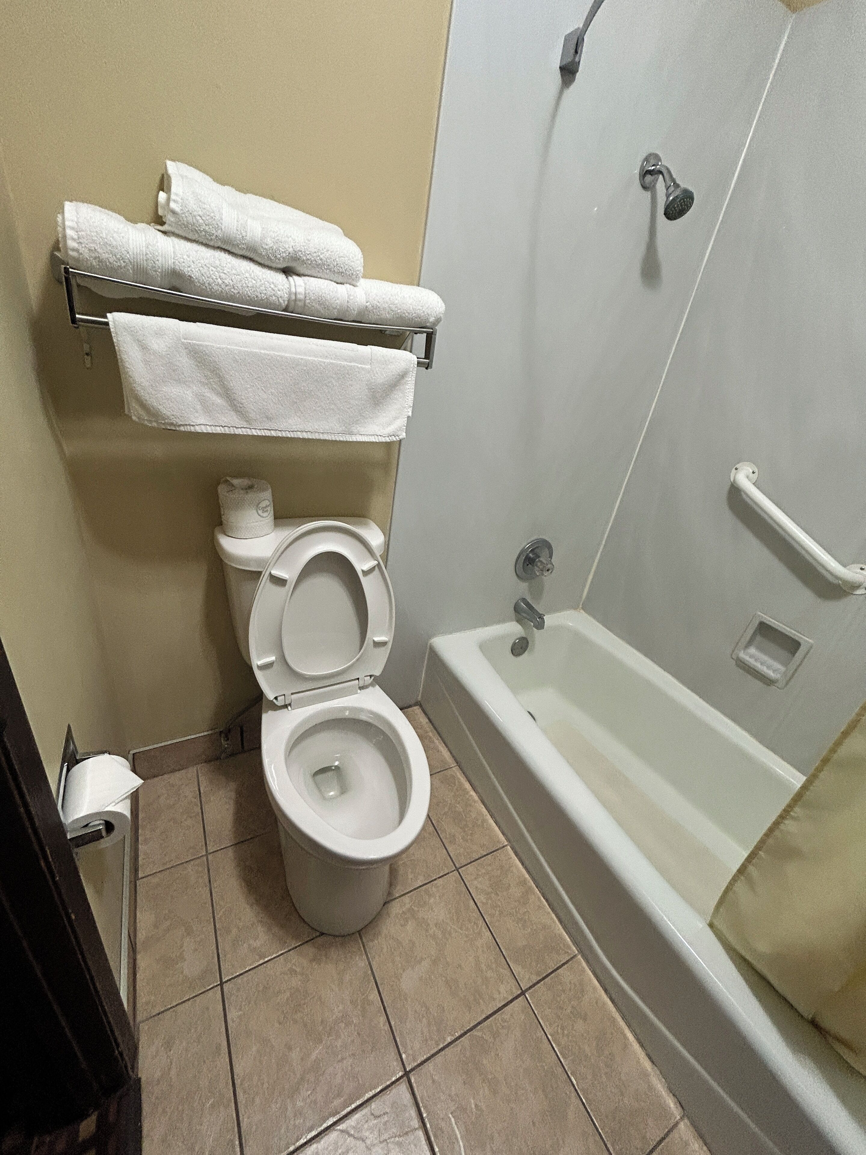 A bathroom with a toilet, a sink, and a bathtub. There are towels hanging on a rack above the toilet.