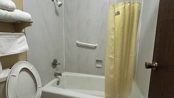A bathroom with a toilet, a shower with a curtain, and a towel rack with towels.