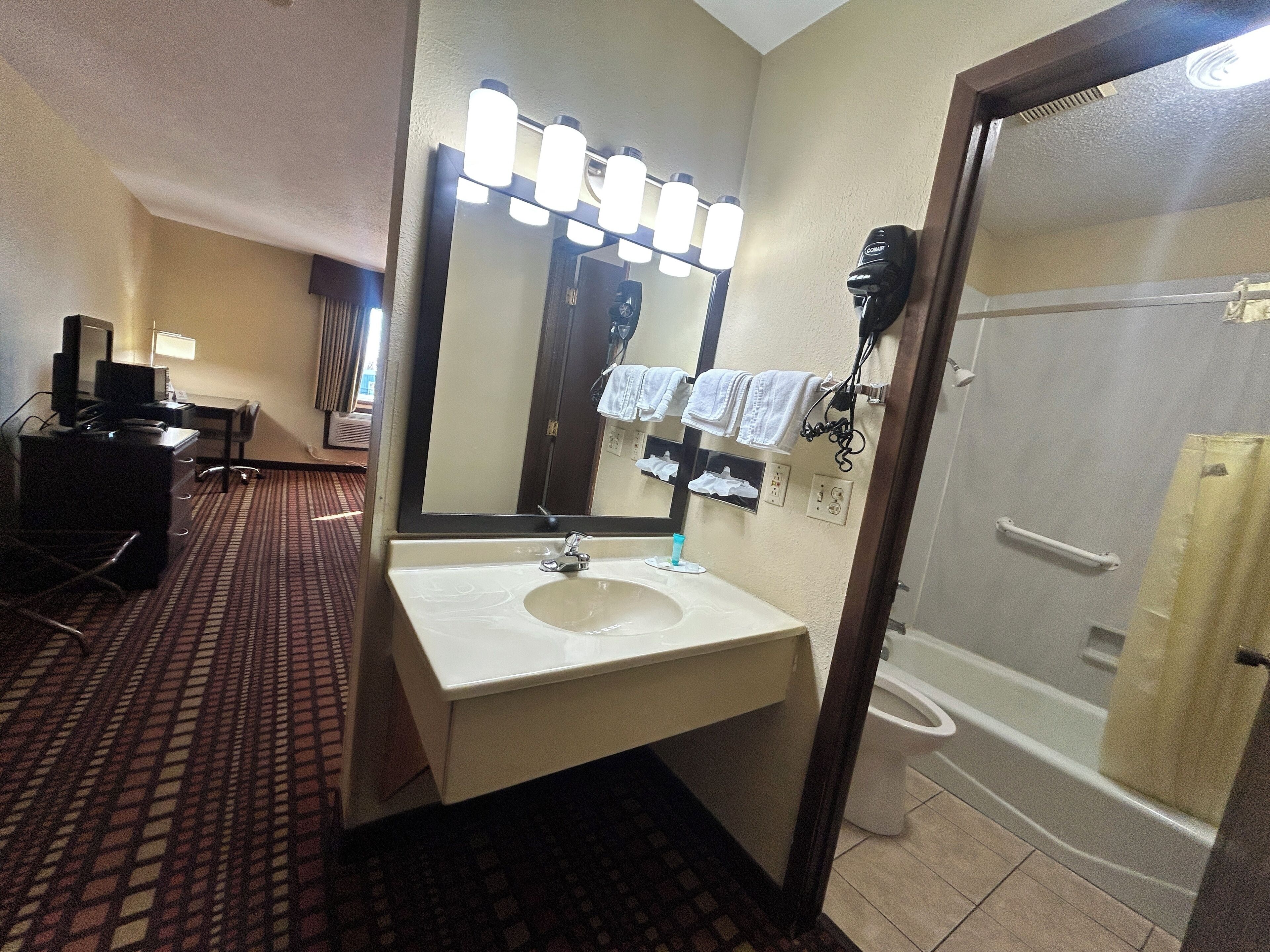A hotel bathroom with a sink, mirror, and shower.