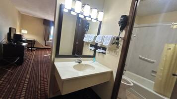 A hotel bathroom with a sink, mirror, and shower.