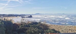 A beach with waves, a sandy shore, and a structure in the distance.