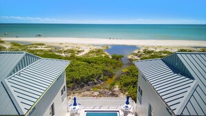 Vista desde un balcón de hotel sobre una playa, una piscina y un cielo despejado.