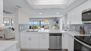 Una cocina moderna con armarios blancos, lavavajillas integrado y una isla grande con un fregadero.