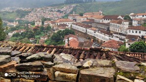 A historic town with terracotta-roofed buildings, cobblestone streets, and a prominent church tower. - Diamond Hostel (Ouro Preto)