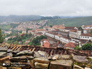 A historic town with terracotta-roofed buildings, cobblestone streets, and a prominent church tower. - Diamond Hostel (Ouro Preto)