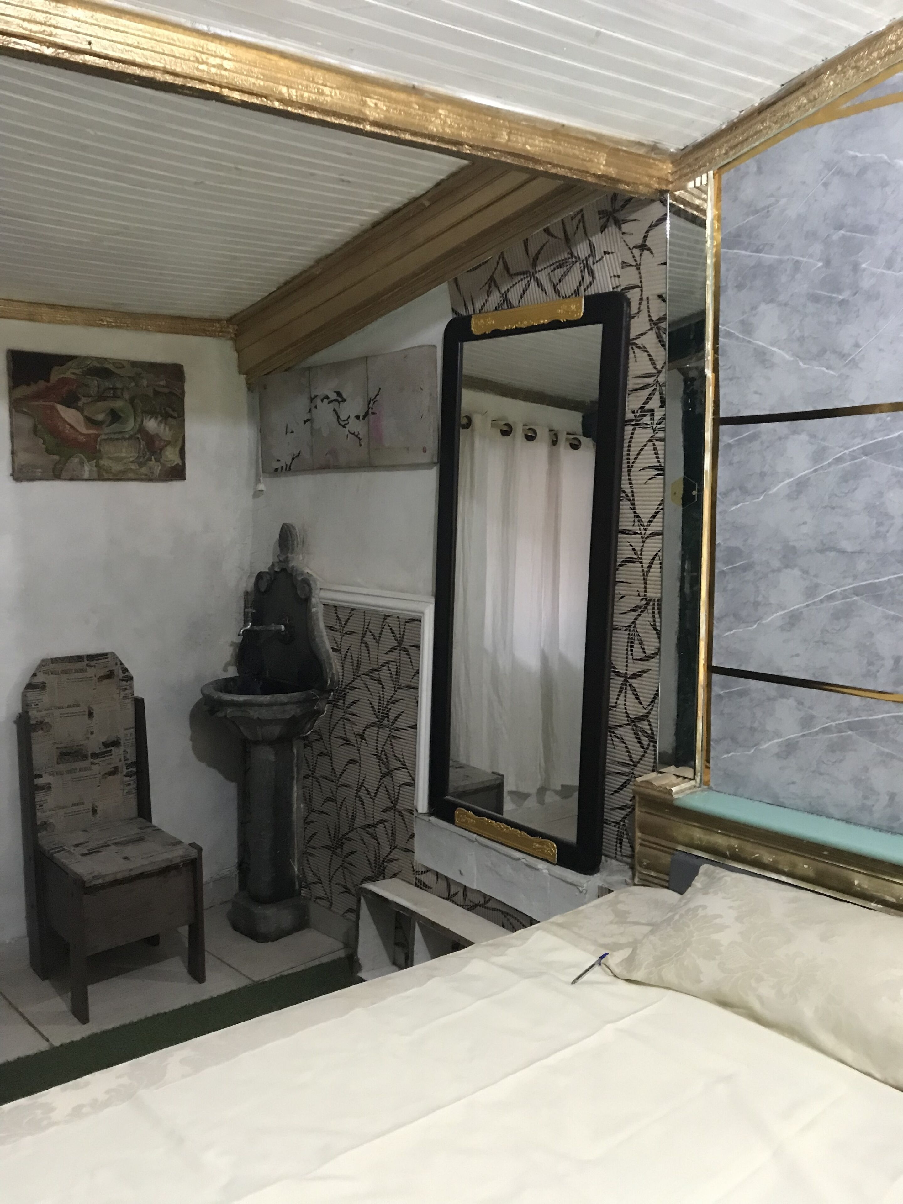 A bathroom with a bed, a sink, and a mirror.