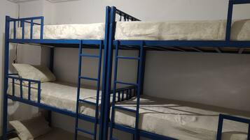 Habitación con literas triples, cada una con colchón y almohadas.