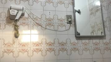 Un baño con baldosas estampadas, un secador de pelo montado en la pared, un espejo y un lavabo.