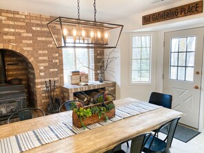 Enjoy meals and social gatherings in The Gathering Place, featuring a rustic fireplace and dining table.