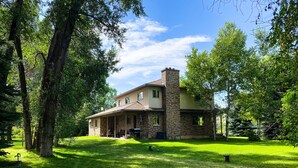 A two-story house with a stone chimney, a covered porch, and a well-maintained lawn. - The Gathering Place on the Teton River (Rexburg)