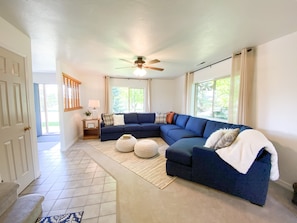 Relax in this inviting living room with a large sofa, side table, and floor-to-ceiling window.