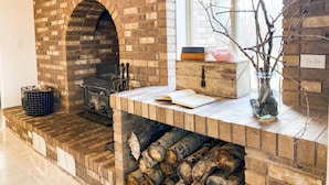 A brick fireplace with a stone archway, a wooden bench, and a vase with branches. - The Gathering Place on the Teton River (Rexburg)