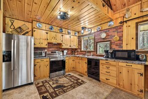 A kitchen with wooden cabinets, stainless steel appliances, and a patterned rug.