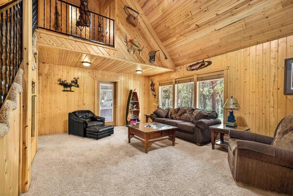 A wooden interior with a staircase, a sofa, a coffee table, and a fireplace.
