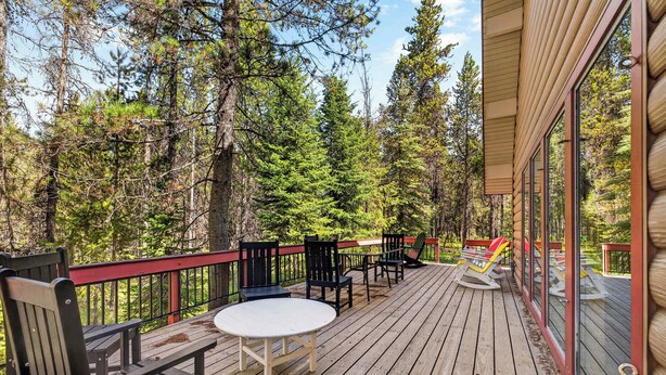A wooden deck with outdoor furniture, surrounded by trees.