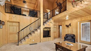 A wooden interior with a staircase, a leather chair, and a television.