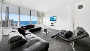 A modern living room with a large window, a sofa, a lounge chair, and a flat-screen TV. - Surfers Paradise Ocean view (Surfers Paradise)