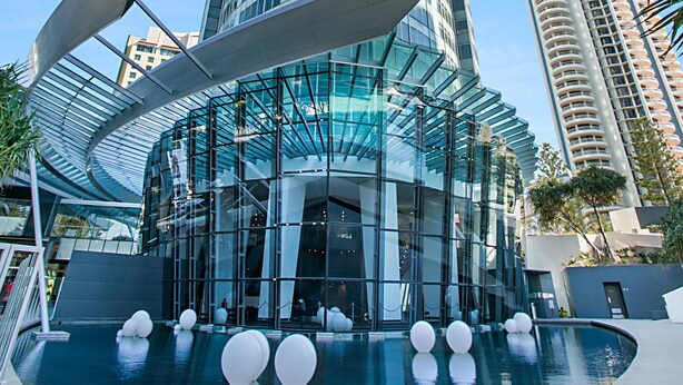 A modern building with a glass facade and a pool area with spherical decorations. - Surfers Paradise Ocean view (Surfers Paradise)