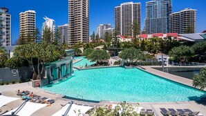 A swimming pool with lounge chairs and a cityscape in the background. - Surfers Paradise Ocean view (Surfers Paradise)