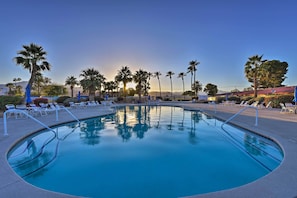 Une piscine à l’eau d’un bleu cristallin, entourée de chaises longues et de palmiers.