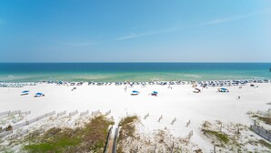Ein Strand mit weißem Sand, einer Holzpromenade und Sonnenschirmen.