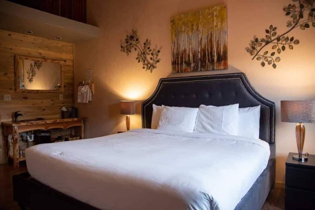 Un dormitorio con una cama grande, cabecera de madera, un espejo y cuadros en la pared.