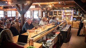 A bar with wooden beams, a long counter, and a barista preparing drinks. - Arrowhead Mountain Lodge (Cimarron)