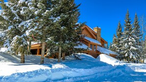 A wooden lodge with a snow-covered roof, surrounded by snow-laden trees and a clear blue sky. - Arrowhead Mountain Lodge (Cimarron)