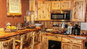 A kitchen with wooden cabinets, a microwave, and various appliances. - Arrowhead Mountain Lodge (Cimarron)