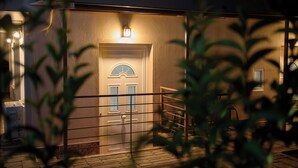 A building with a gated entrance, a light fixture above the door, and a small staircase leading to the entrance. - Artemissoula (Spata-Artemida)