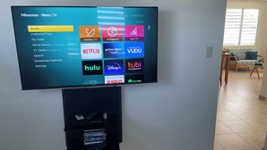 A flat-screen TV mounted on a wall displaying various streaming services. - MTB  & Beach House in Cabo Rojo (boqueron)