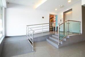 A modern interior with a metal staircase, a lift, and a glass railing. - Hotel Kepong (Kuala Lumpur)