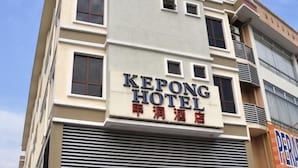 Un bâtiment d'hôtel avec une enseigne indiquant « HÔTEL KEPONG » et des caractères chinois en dessous.