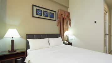 A hotel room with a large bed, two bedside tables, a lamp, a telephone, and a framed picture on the wall.
