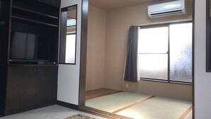 A room with a tatami mat floor, a sliding door, a ceiling fan, and an air conditioning unit. - Ever Garden (Miyoshi)