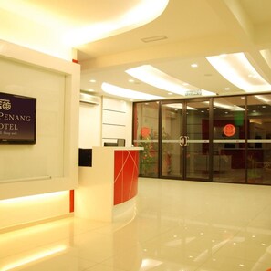 A hotel reception area with a modern design, a reception desk, and a glass door entrance. - Old Penang Hotel - Penang Times Square (George Town)