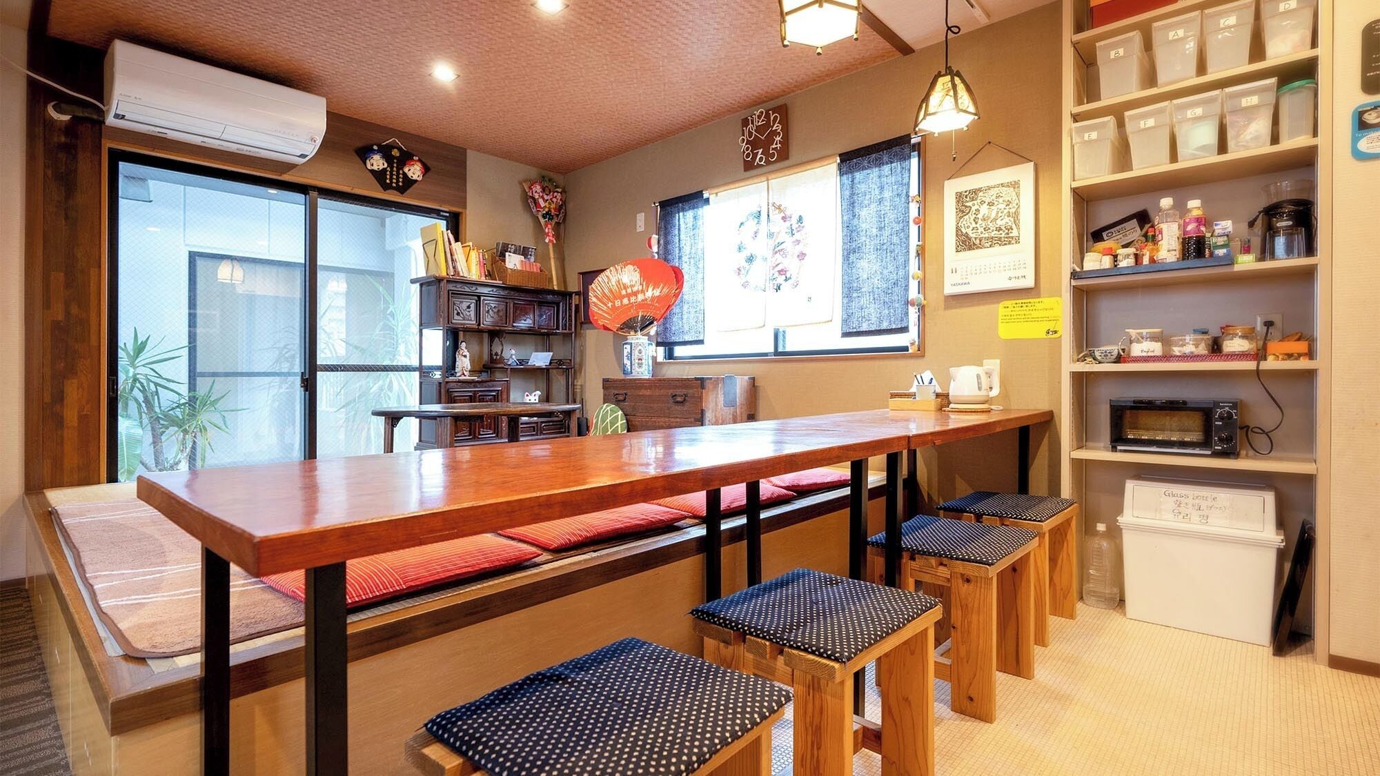 Un accogliente caffè con un tavolo di legno, panche ed scaffali pieni di oggetti diversi.