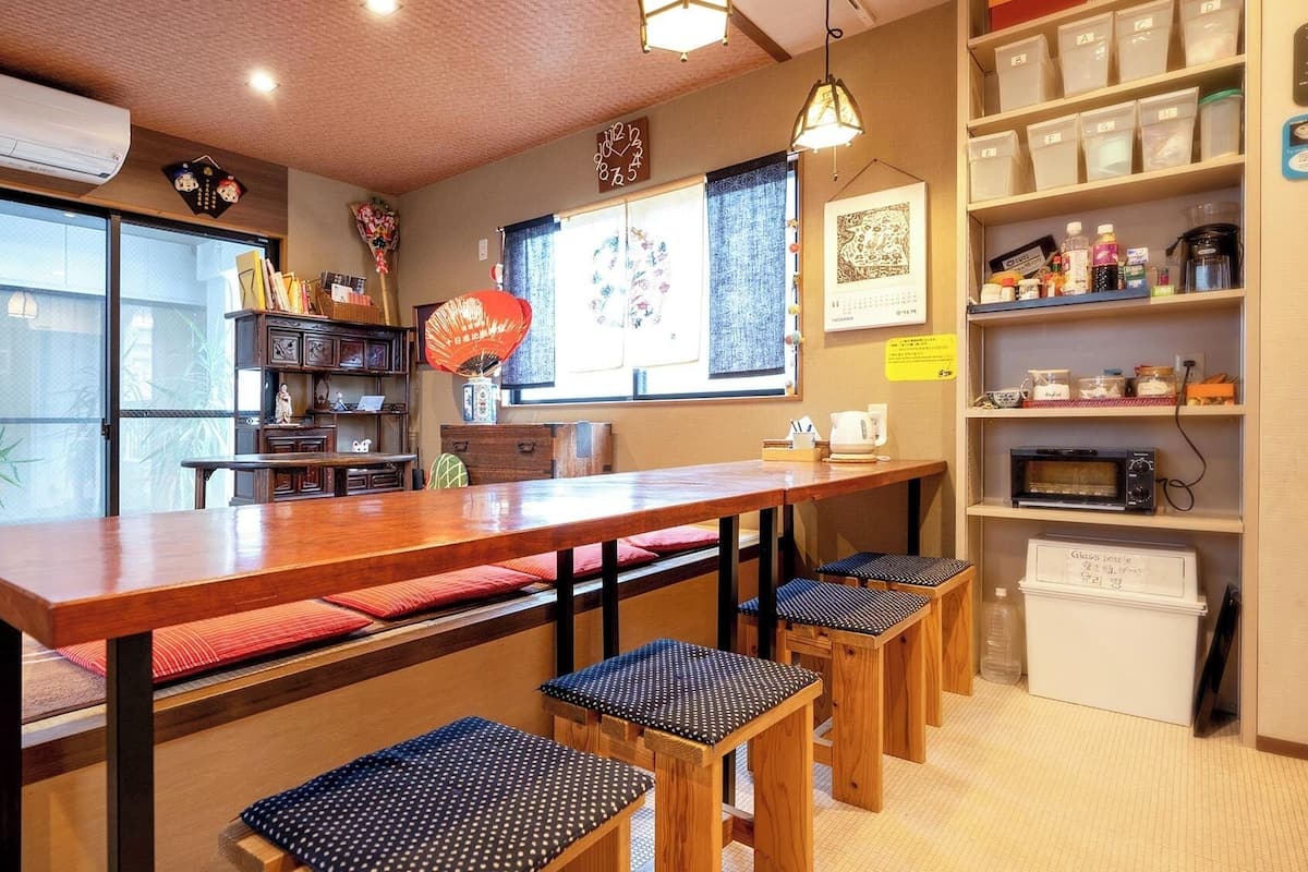 Un café chaleureux avec une table en bois, des bancs et des étagères remplies de divers objets.