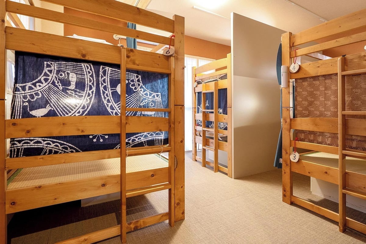 Une chambre avec des lits superposés, chacun étant muni d’une étiquette numérotée, et un rideau à motifs.
